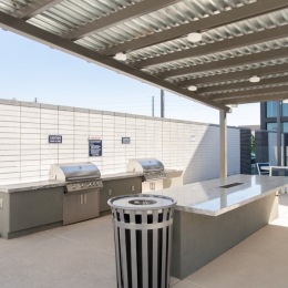 a covered grill area with a bar and a trash can